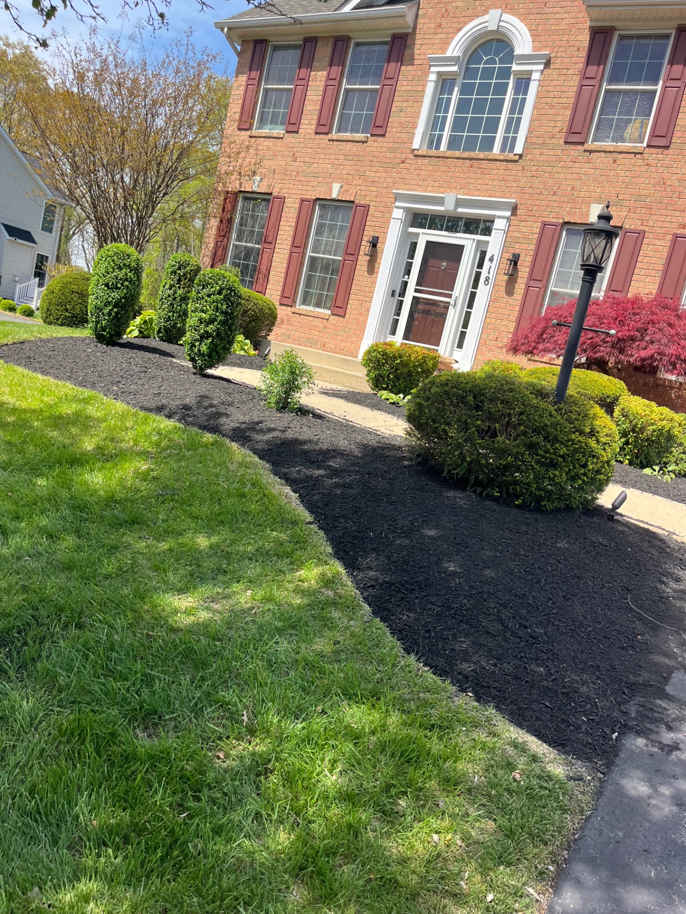 Black mulch beds and trimmed shrubs at a brick home